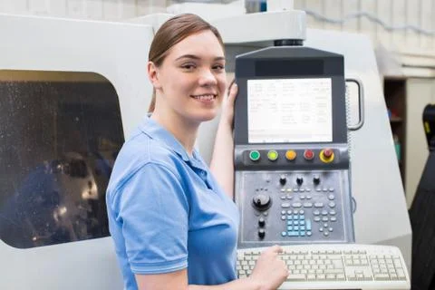 Portrait Of Female Apprentice Engineer Operating CNC Machine In Factory Stock Photos