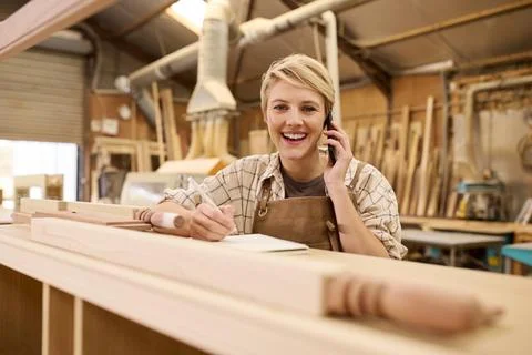 Portrait Of Female Apprentice Working As Carpenter In Furniture Workshop Making Stock Photos