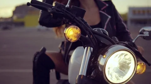 Portrait of a female biker in leather jacket and shorts sitting on her bike and Stock Footage