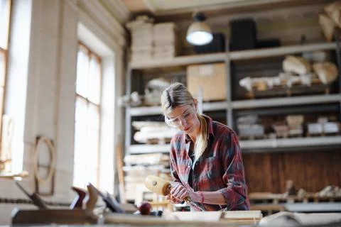 Portrait of female carpenter with goggles working on her product. Small business Stock Photos