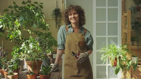 Portrait of Female Gardener with Pruning Scissors Standing next to Potted Plants Stock Footage 255699345