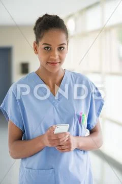 Portrait Of A Female Nurse Text Messaging With A Mobile Phone