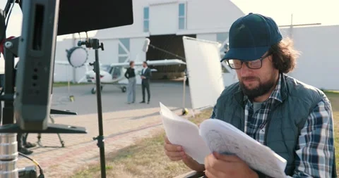 Portrait of filmmaker reading script outdoors on set. Handsome Caucasian male Stock-Footage 141688583