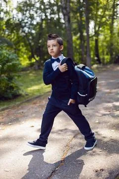 Portrait first-grader boy in a uniform with a bow tie and a backpack is stand Stock-Fotos