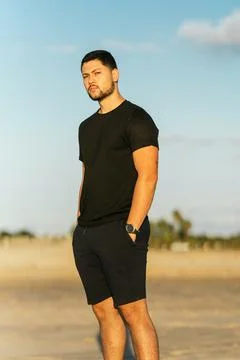 Portrait of a fit man standing on the sand of the beach with relaxed expression Stock Photos