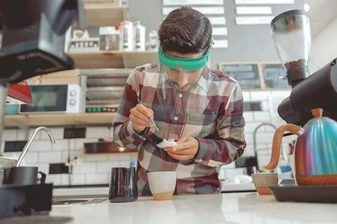 Portrait of focused barista drawing pattern on milk foam Stock Photos
