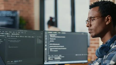 Portrait of focused software developer writing code arranging glasses sitting at Stock Photos