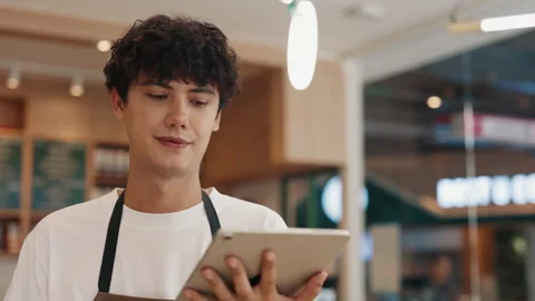 Portrait of focused waiter inputting order data on tablet computer in cafe Video stock 309938274