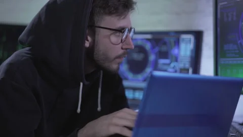 Portrait of focused young man hacking web site or launching computer virus using Video stock 141958196