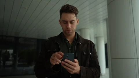 Portrait of focused young man looking to smartphone screen with serious Stock Footage 296582893