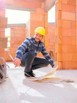 Portrait of foreman with construction plan and pocket rule at construction site Stock Photos