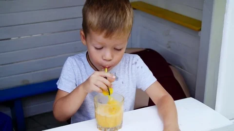 Portrait, a four-year-old boy spoils with juice, lets bubbles into juice through Stock Footage 80305116