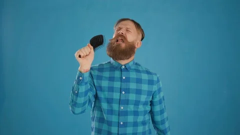 Portrait of a freak guy combing his hair and singing into a comb Stock Footage 127624113