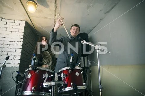 Portrait of friends playing drum kit at home Stock Photos
