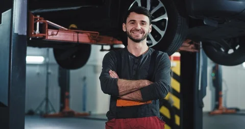 Portrait in front of the camera smiling large mechanic guy in a modern auto Stock Footage 121274609