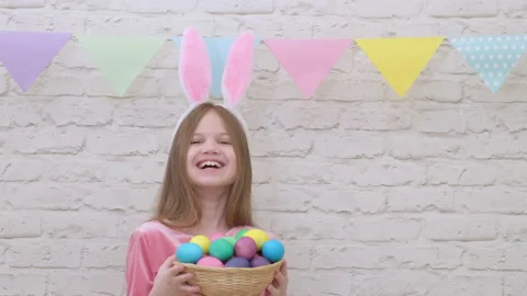 Portrait of funny Easter child wearing bunny ears with colorful eggs Video stock 233588749
