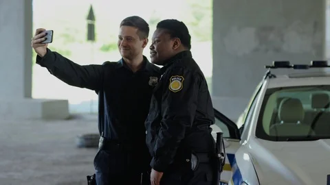 Portrait funny two men cops stand near patrol car take selfie smile accepting Stock Footage 112955126
