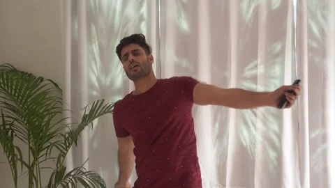 Portrait of funny young man dancing and singing enjoying music holding remote. Video stock 151100769