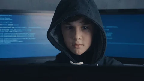 Portrait of a Genius Boy Hacker Prodigy in the hood working on computer in Vidéo 101978790