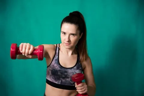 Portrait of a girl performs exercises using dumbbells. Stock Photos