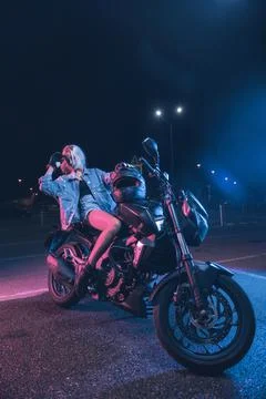 Portrait of a girl in the rays of neon light on a motorbike Stock Photos