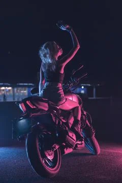 Portrait of a girl in the rays of neon light on a motorbike Stock Photos