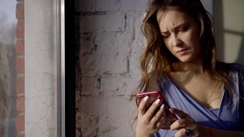 Portrait of a girl with a serious brooding face, who sits near the window and Stock Footage 102436299