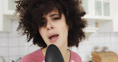 Portrait of girl singing in kitchen using spoon as microphone looking at camera. Stock Footage 127083614