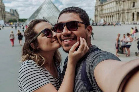 Portrait of girlfriend kissing boyfriend against Musee du Louvre in city Stock Photos