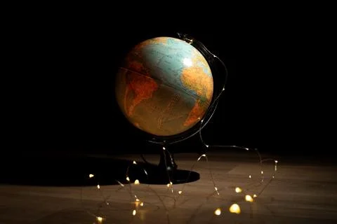 A portrait of a globe stand surounded by lights on a wooden floor in a dark r Stock Photos