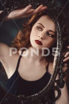 A portrait of a gorgeous beautiful young woman looking through the frame of t Stock Photos