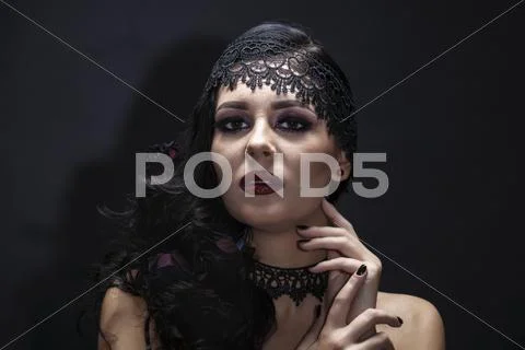 Portrait of a gorgeous brunette with a hat over black background. Halloween. Stock Photos