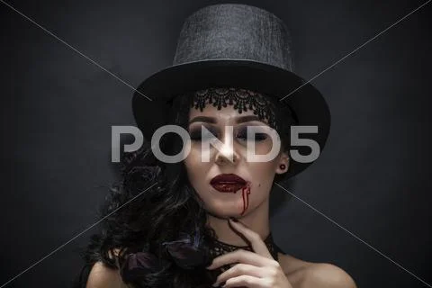 Portrait of a gorgeous brunette with a hat over black background. Halloween. Stock Photos