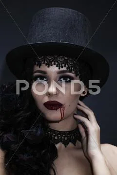Portrait of a gorgeous brunette with a hat over black background. Halloween. Stock Photos