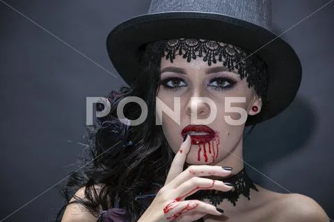 Portrait of a gorgeous brunette with a hat over black background. Halloween. Stock Photos