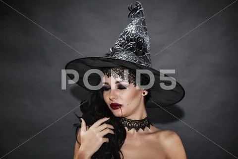 Portrait of a gorgeous brunette with a hat over black background. Halloween. Stock Photos