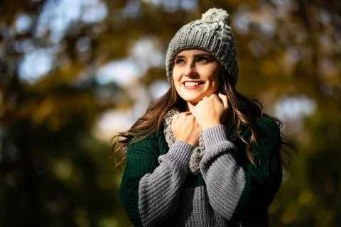 Portrait of gorgeous young woman in knitted beanie and scarf in autumn in par Stock Photos