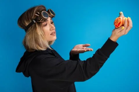 Portrait of goth girl wearing steam punk glasses wondering at an orange carved Stock Photos