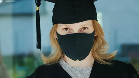 Portrait of a graduate in a robe cap with a protective mask on her face Stock Footage 137100665