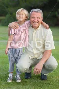 Portrait of grandfather crouching beside grandson Stock Photos