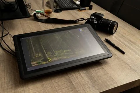 A portrait of a graphical drawing pen tablet and its stylus lying on a wooden Stock Photos