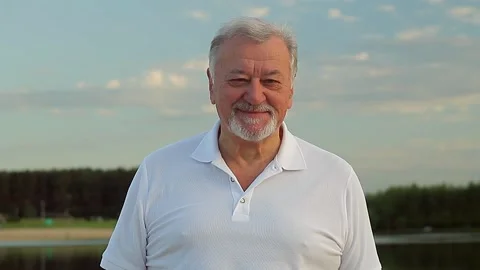 Portrait of a gray-haired senior man with a beard looks at the camera and smiles Stock Footage 168537481