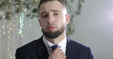 A portrait of a groom with a beard in a solid suit straightens his tie. Stock Footage 166887484