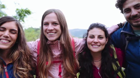 Portrait of group of friends looking at camera during a hike. They are embracing Stock Footage 240983310