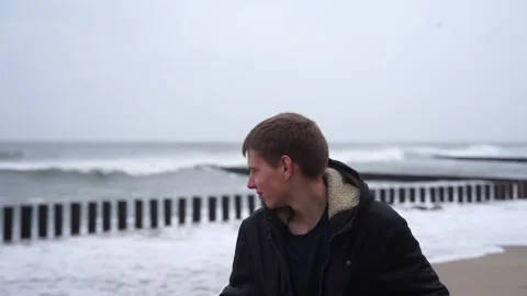 Portrait of a guy against the backdrop of a stormy sea with flying seagulls Video stock 227469125