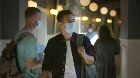 Portrait of guy with backpack wearing safety mask walking in college corridor Stock Footage 139043378