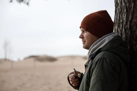 Portrait of a guy in a jacket and a cap by a tree Foto stock