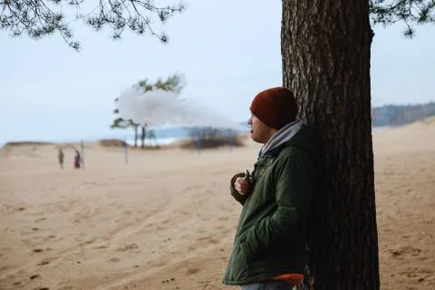 Portrait of a guy in a jacket and a cap by a tree Foto stock