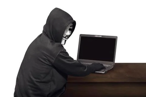 Portrait of hacker man with mask looking back while typing laptop on desk Stock-Fotos
