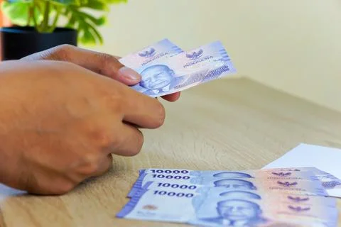 Portrait of a hand counting Rupah notes on a table Stock Photos